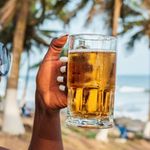 Woman drinking a beer out at a beach bar